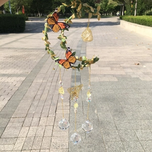 Detail of moon-shaped wind chime with orange butterflies and yellow crystal stones