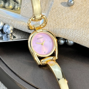 Detailed close-up of a horseshoe-shaped gold alloy watch with a pink dial and rhinestone markers