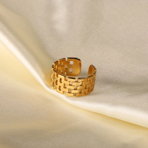 Detail of 18K gold-plated stainless steel ring with woven texture on beige silk fabric
