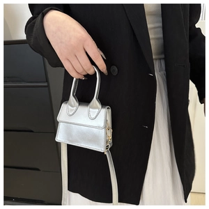 Nahaufnahme einer silbernen Metallic-Minihandtasche mit langem Gurt von einem Model