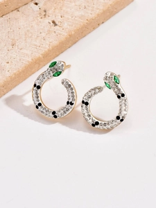 Close-up of snake earrings with white enamel, zircon inlay and green stone eyes