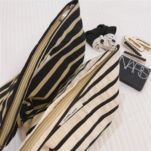 Close-up of striped cotton canvas makeup bags with silver metal zippers and woven labels