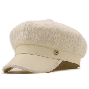 Detail of cream white baker boy hat featuring knitted fabric and leather visor texture