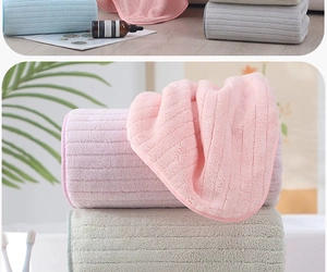 Detailed view of thick striped coral fleece towels in blue, pink, and beige soft textures