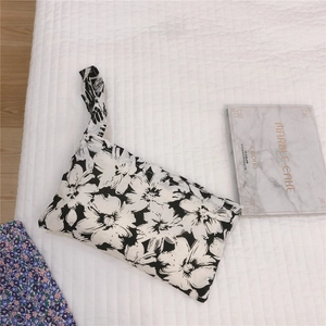 Vue de dessus d'une pochette de poignet en tissu à motif floral noir et blanc