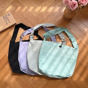 Borse a tracolla in nylon capienti in quattro colori pastello su pavimento in legno