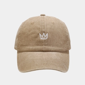 Detailed close-up of white crown embroidery on khaki washed cotton baseball cap