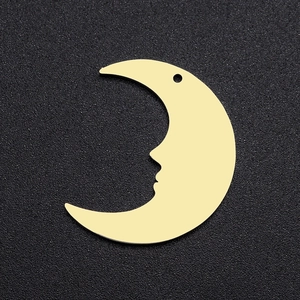 Macro shot of gold stainless steel crescent moon pendant with face profile on black background