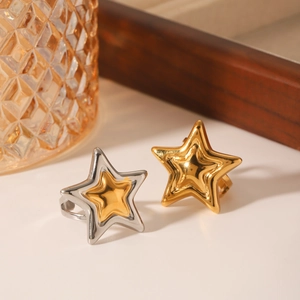Minimalist bicolor star rings in gold and silver stainless steel on a white surface