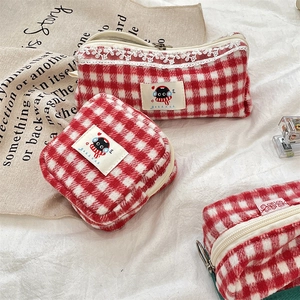 Detail view of red and white checkered plush bags with cat patches and lace trim