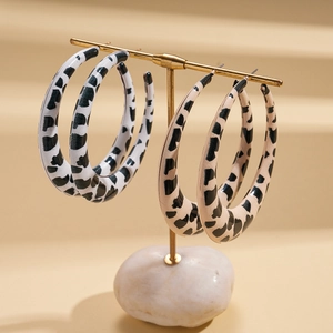 Chic leopard print resin hoop earrings in black and beige on golden jewelry stand