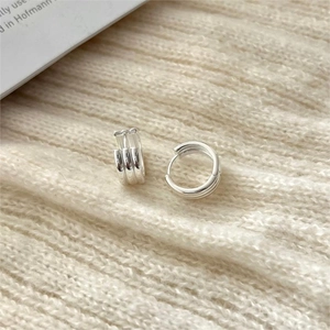 Minimalist S925 sterling silver triple-hoop earrings on soft knit fabric background