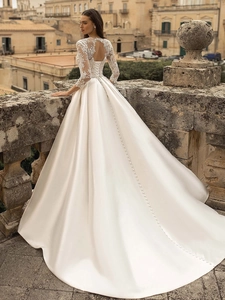 Detailed back view of white lace satin wedding dress with long sleeves and elegant train