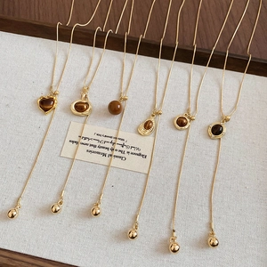 Detail of adjustable golden necklaces with tigers eye heart and geometric pendants