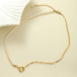 Detail of French vintage pearl necklace with gold paperclip chain on beige leather