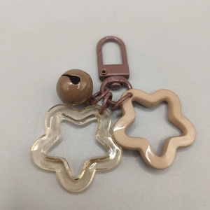 Detail of star keychain with brown bell and colorful acrylic pendants on grey background