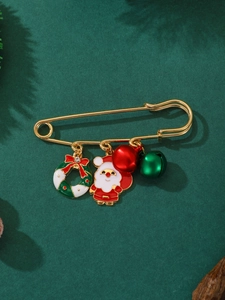 Detailed view of a gold safety pin brooch with Santa and Christmas wreath charms