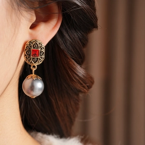 Nahaufnahme der Vintage Gold-Ohrringe mit rotem Edelstein und grauer Perle