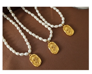Detailed view of freshwater pearl necklace with gold tulip flower embossed pendant