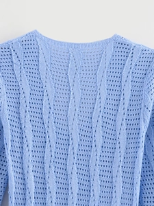 Detail of light blue knit top featuring vertical wave textures and hollow-out crochet pattern