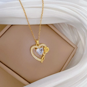 Detail of gold heart pendant with crystal zircon and rose flower on silk fabric