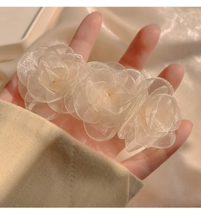 Detailed shot of triple champagne organza camellia flowers on a feminine hair clip