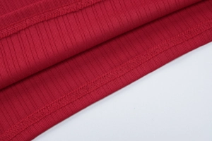 Gros plan détaillé sur la texture du tissu côtelé rouge et les coutures de l'ensemble
