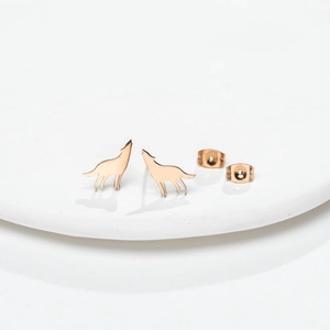 Howling wolf stud earrings in rose gold finish on white ceramic display tray