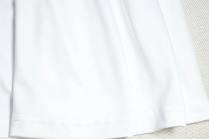 Gros plan détaillé montrant les coutures fines et la texture du tissu de la robe blanche
