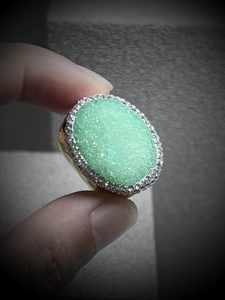 Close-up of a wide adjustable gold ring featuring a green druzy quartz crystal stone