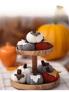 Detailed close-up of eight knitted pumpkins on a tiered wooden tray for harvest decor
