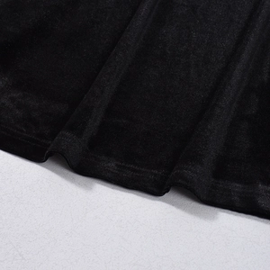 Detail of soft black velvet fabric texture and elegant draping on a long sleeve dress