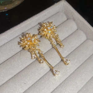 Detail of gold fireworks earrings with pearls and zircon tassels on grey velvet