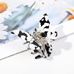 Detail of butterfly hair claw with black and white patterns and gold metal spring