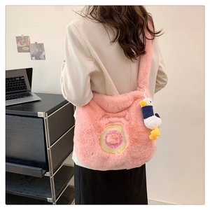 Pink plush shoulder bag with donut embroidery and duck charm on model in home setting
