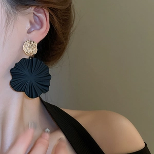 Nahaufnahme der schwarzen Spiral-Blumenohrringe mit goldenem Metallstecker am Modell