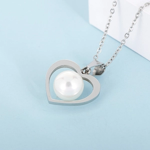 Close-up of a silver hollow heart pendant with a white pearl on a delicate O-chain