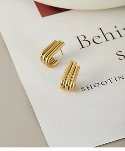 Detailed macro view of gold-plated ribbed titanium steel hoop earrings with high polish