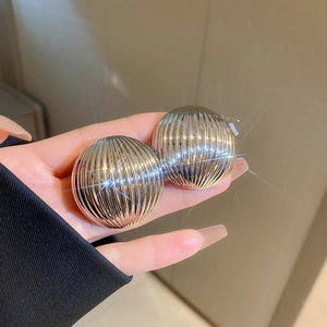 Detailed close-up of spherical silver stud earrings with polished vertical striped texture