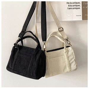 Detail view of small corduroy Boston bags in black and beige with adjustable straps