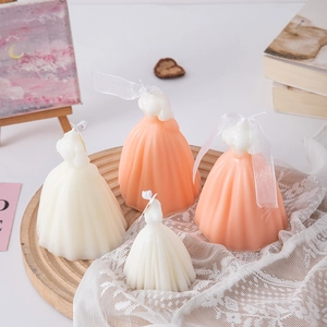 Detailed view of large and small wedding dress candles in ivory and peach on lace