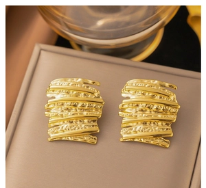 Detailed close-up of 18k gold irregular hammered texture earrings on a jewelry box