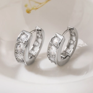 Eleganti orecchini a cerchio placcati oro 18K con tre zirconi in un vassoio bianco