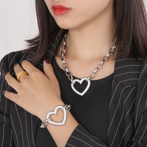 Detail of silver chunky chain set with pave-textured heart pendant on a female model