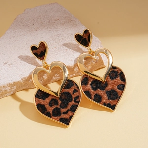 Macro shot of leopard print heart earrings on stone with elegant golden metal edges