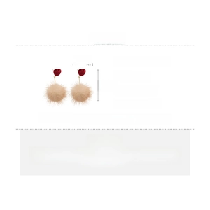 Gros plan de boucles d'oreilles cœur en tissu rouge avec pompons crème sur argent