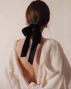Elegant black silk long bow hair ribbon styled on a low ponytail with minimalist French aesthetic