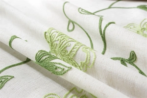 Close-up of green botanical embroidery on beige waterproof linen Christmas tablecloth