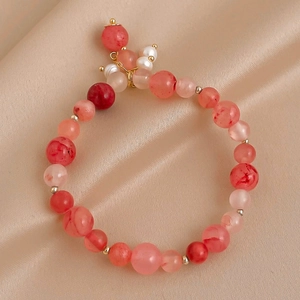 Détail macro du bracelet perlé élastique avec cristaux rouges et perles dorées
