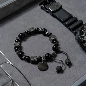 Détail d'un bracelet pour homme en perles d'onyx, pierres de lave et breloques